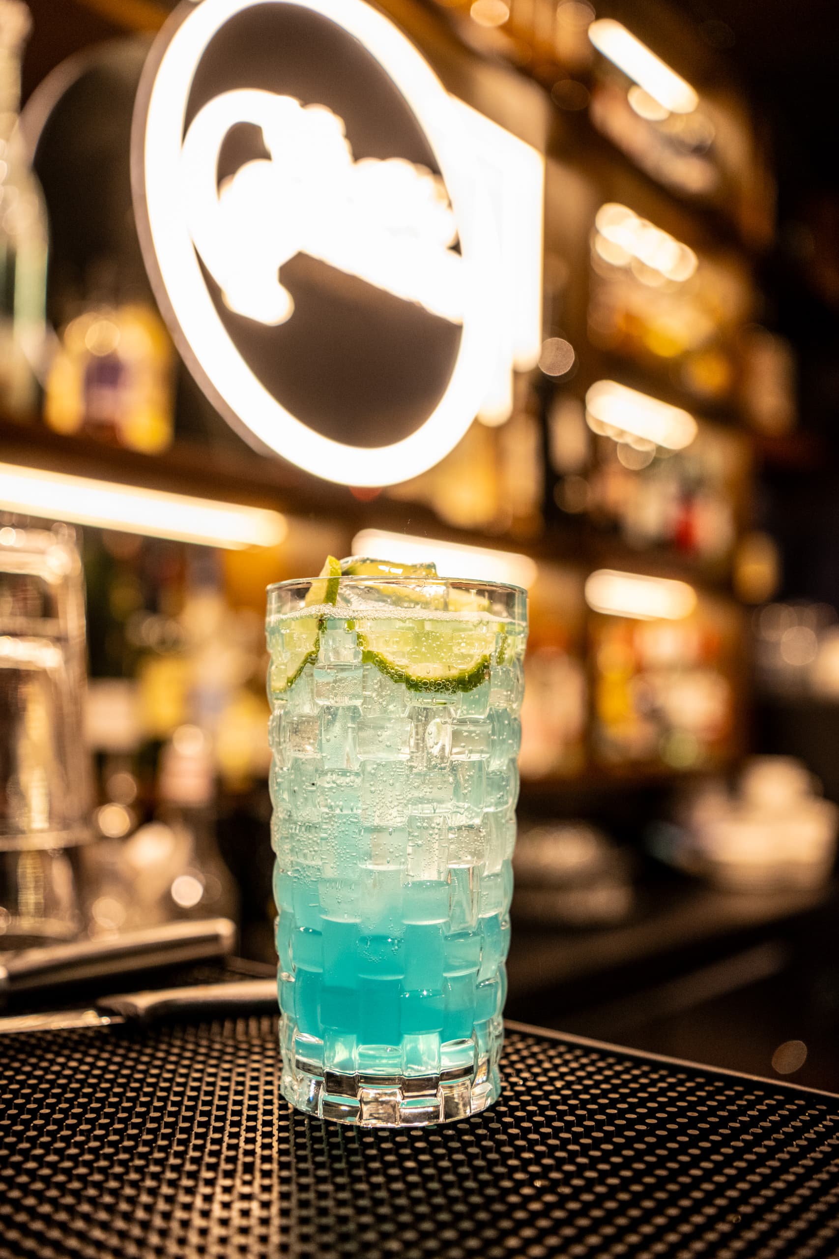 Blauer Drink mit Eis und Limette vor dem beleuchteten Casablanca-Schriftzug