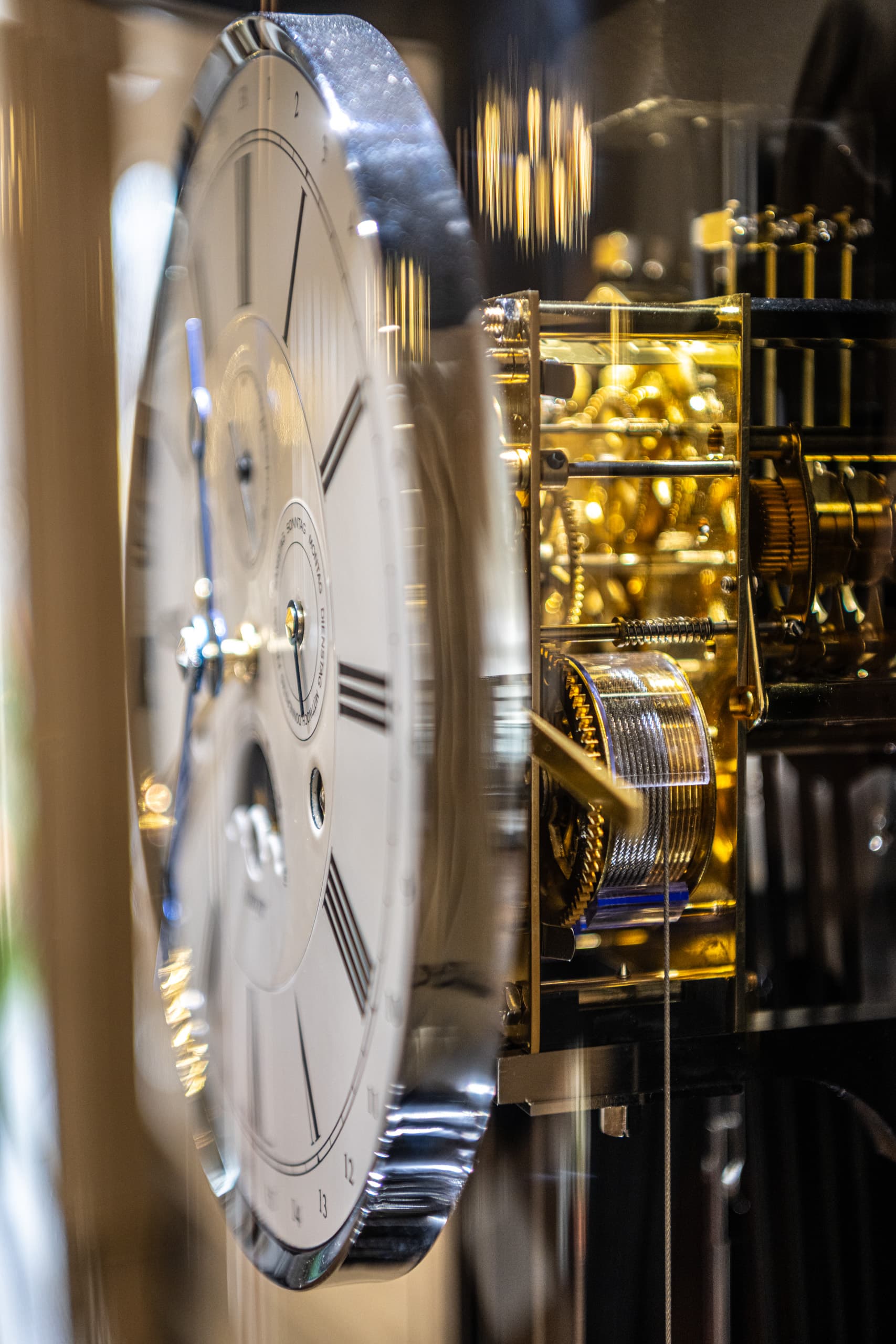 Zifferblatt und goldfarbenes Uhrwerk einer Standuhr im Foyer