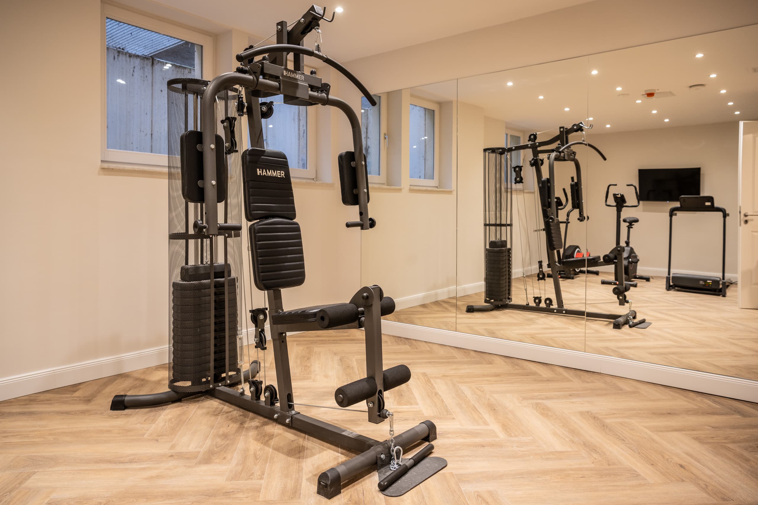 Kraftstation vor der großen Spiegelwand im Fitnessraum